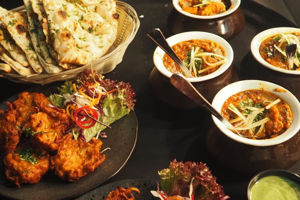 Indian home-cooked meal with curry, naan, and traditional dishes